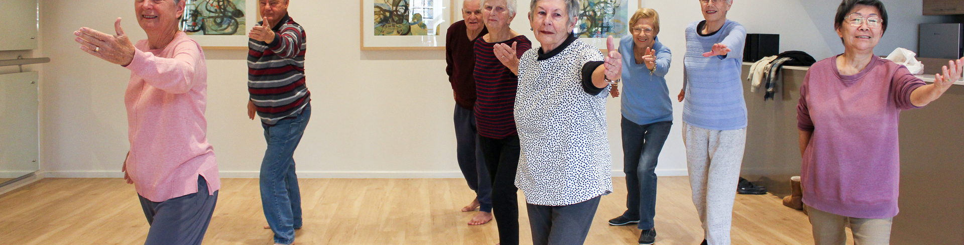 Robin and John lead beginner Tai Chi at Parkland Villas Booragoon. There are 8 people enjoying Tai Chi class in the village community centre.