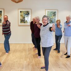 Robin and John lead beginner Tai Chi at Parkland Villas Booragoon. There are 8 people enjoying Tai Chi class in the village community centre.