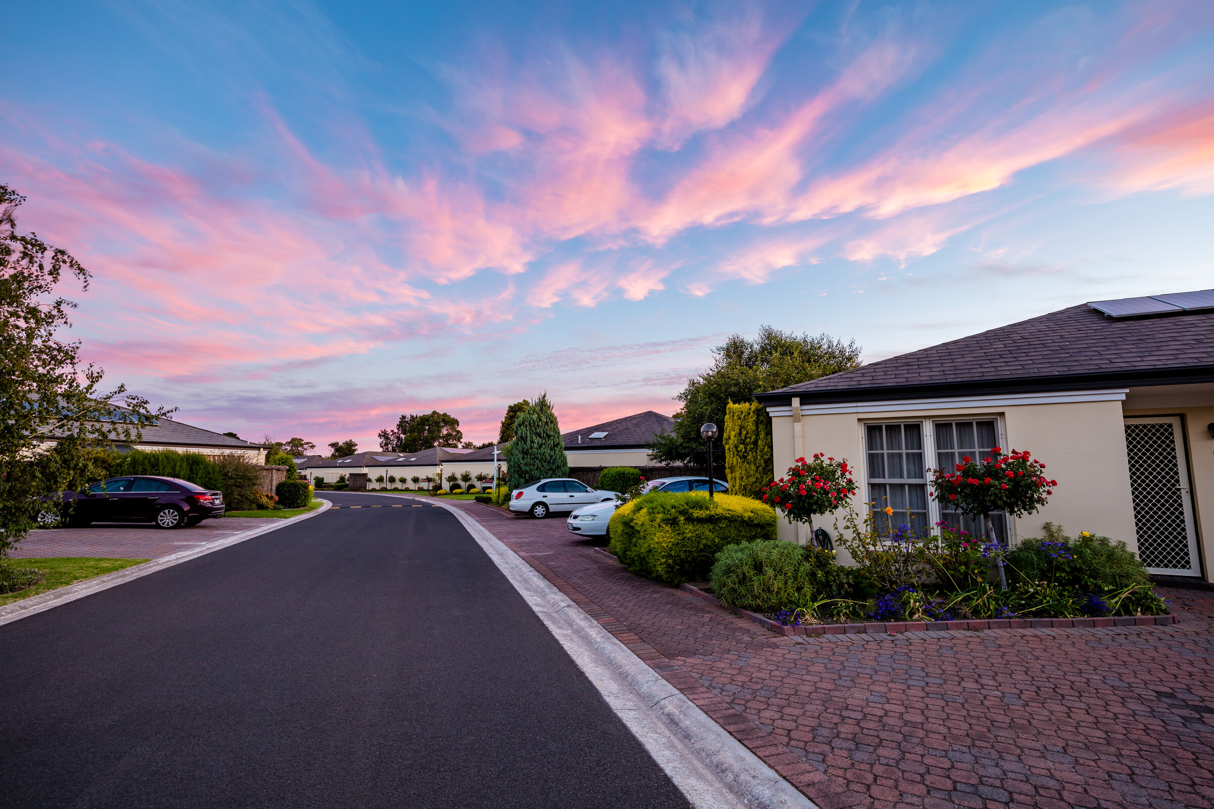 Port Phillip Village evening image of road lined with houses and gardens