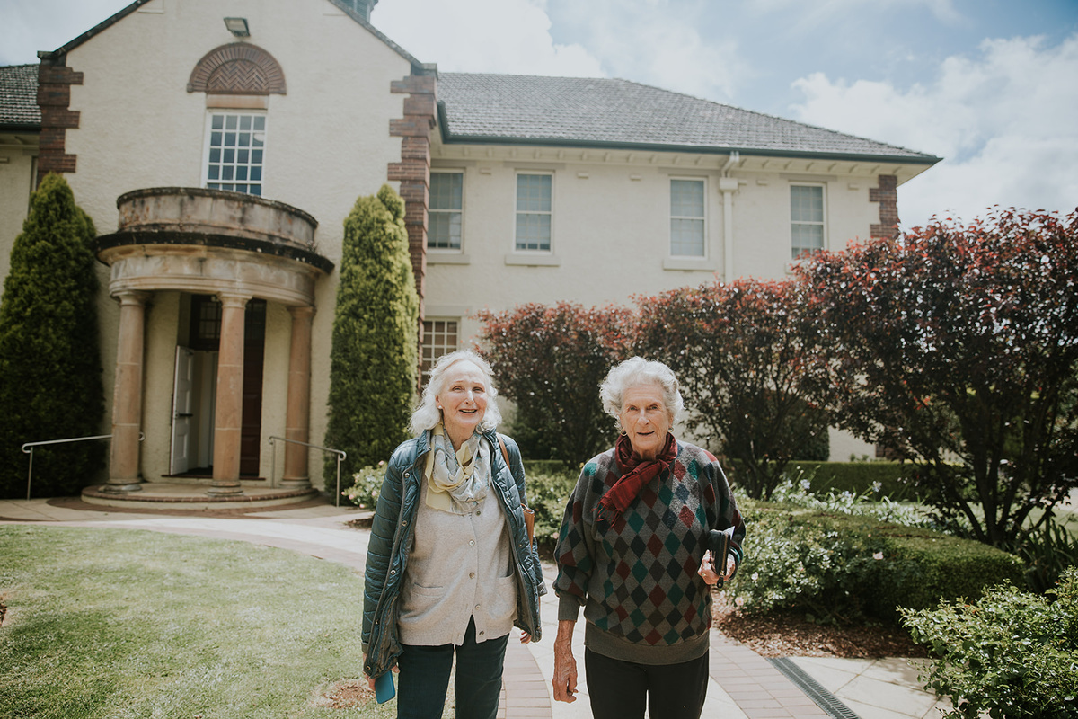 Two senior ladies in winter clothing taking a walk outside the retirement village