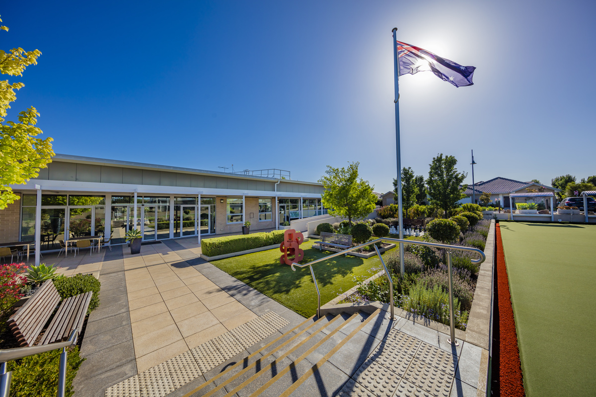 Caesia Gardens landscaping beside main building with modern statue artwork, bowling green and flagpole