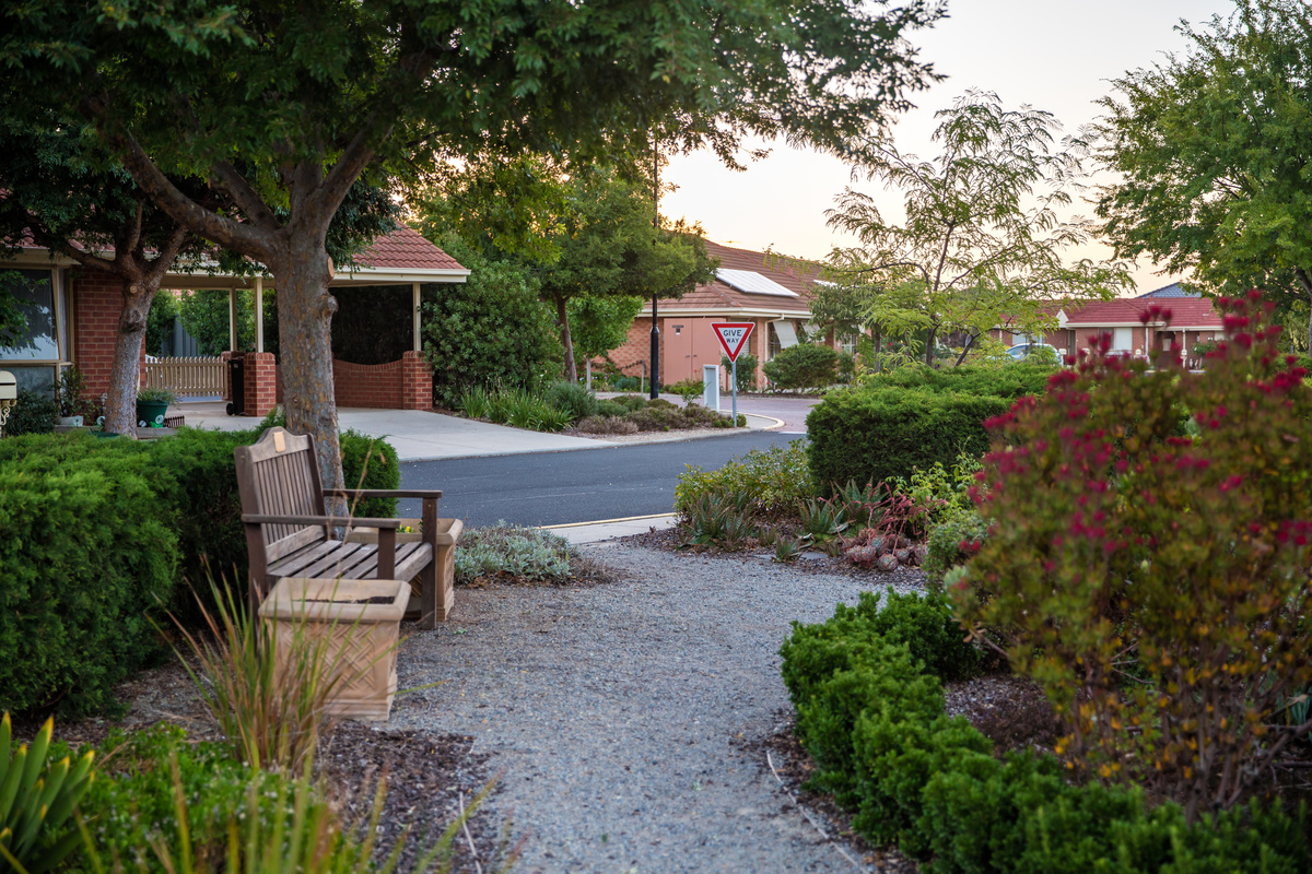 Windsor Park looking from trees and communal garden area with seat over road towards home lined with homes