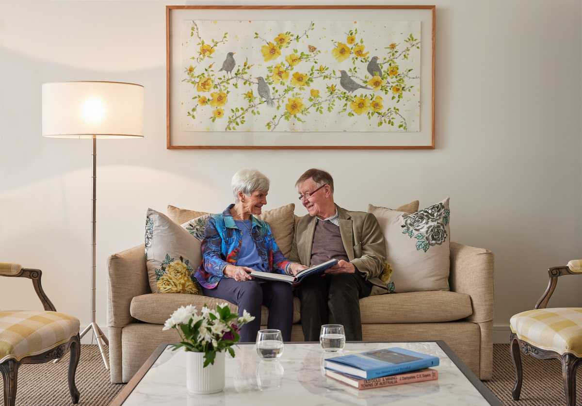 senior couple sitting on a couch together in the living room and talking to each other