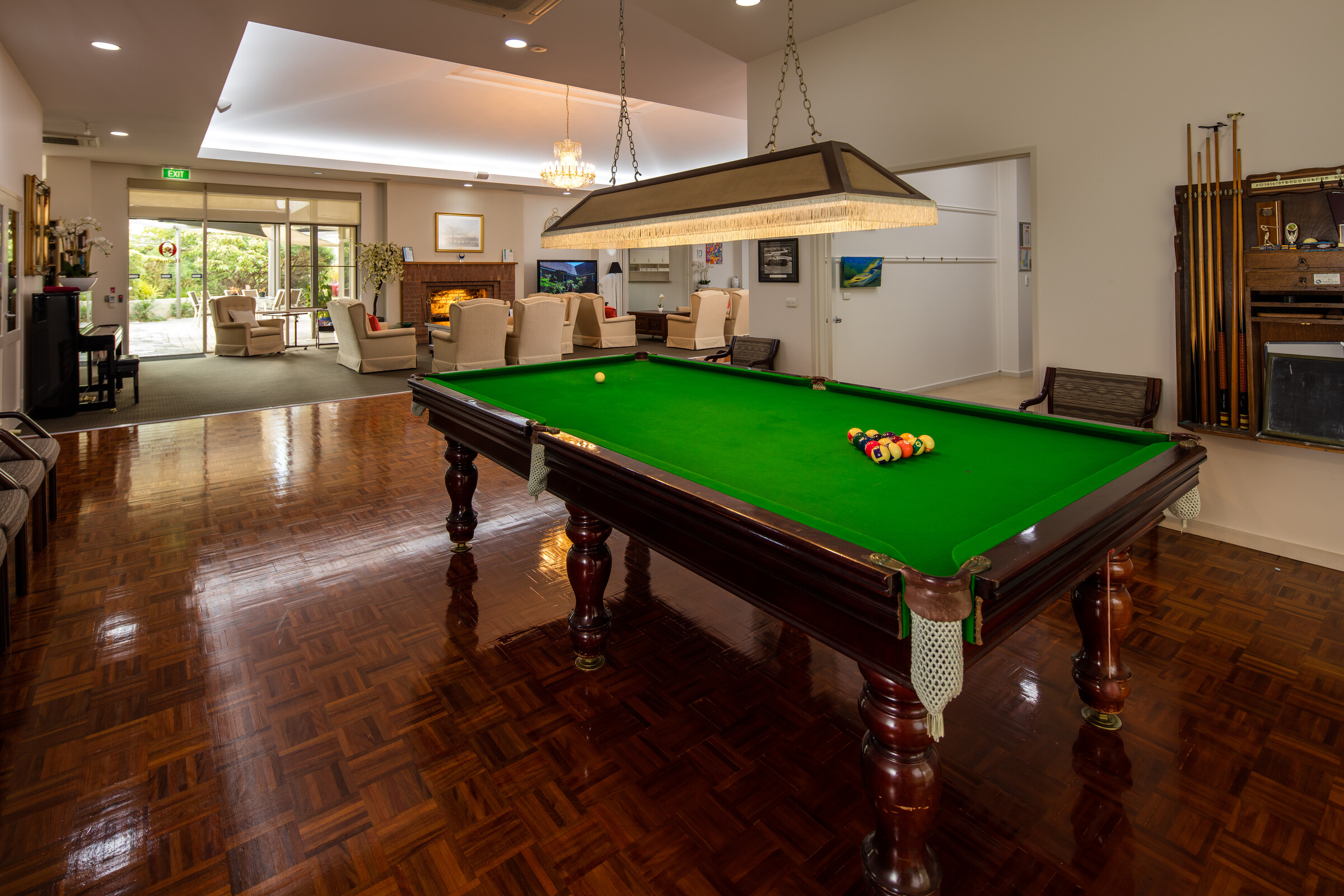 Highvale Village pool table room with lounge, piano and open fireplace in the background